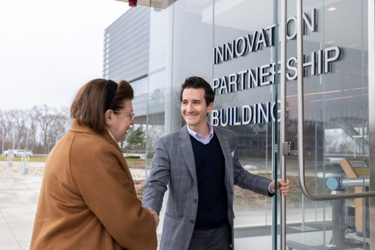Man greeting woman into the Innovation Partnership Building